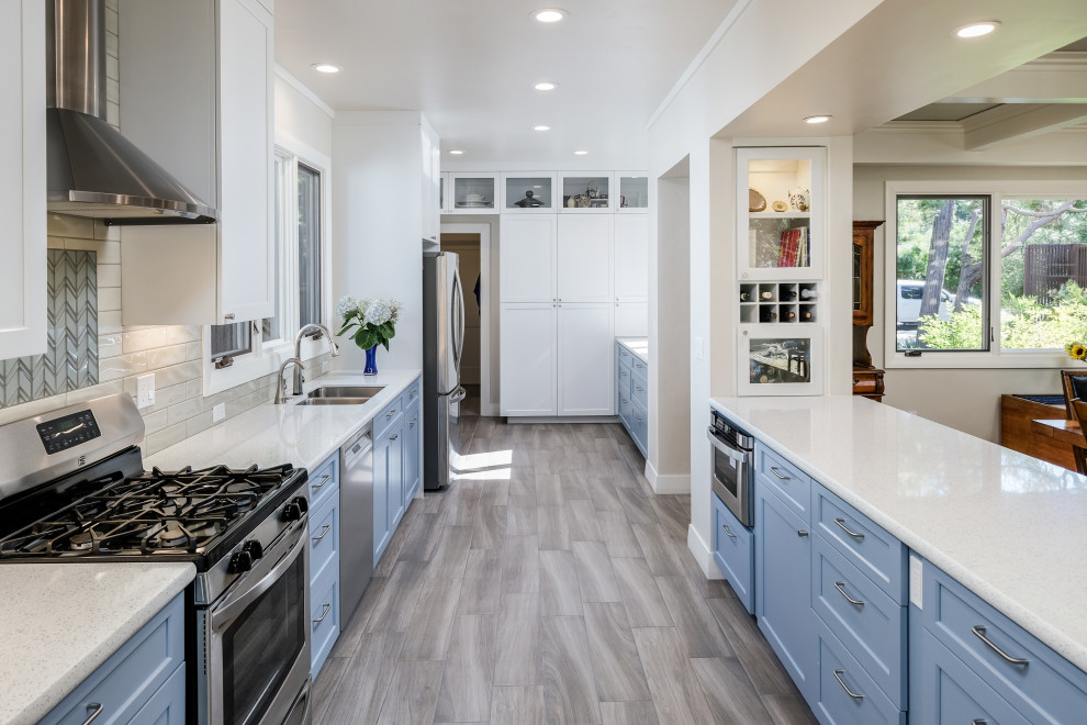 Design ideas for a traditional galley kitchen pantry in Sacramento with a submerged sink, shaker cabinets, blue cabinets, composite countertops, white splashback, metro tiled splashback, stainless steel appliances, porcelain flooring, grey floors and white worktops.
