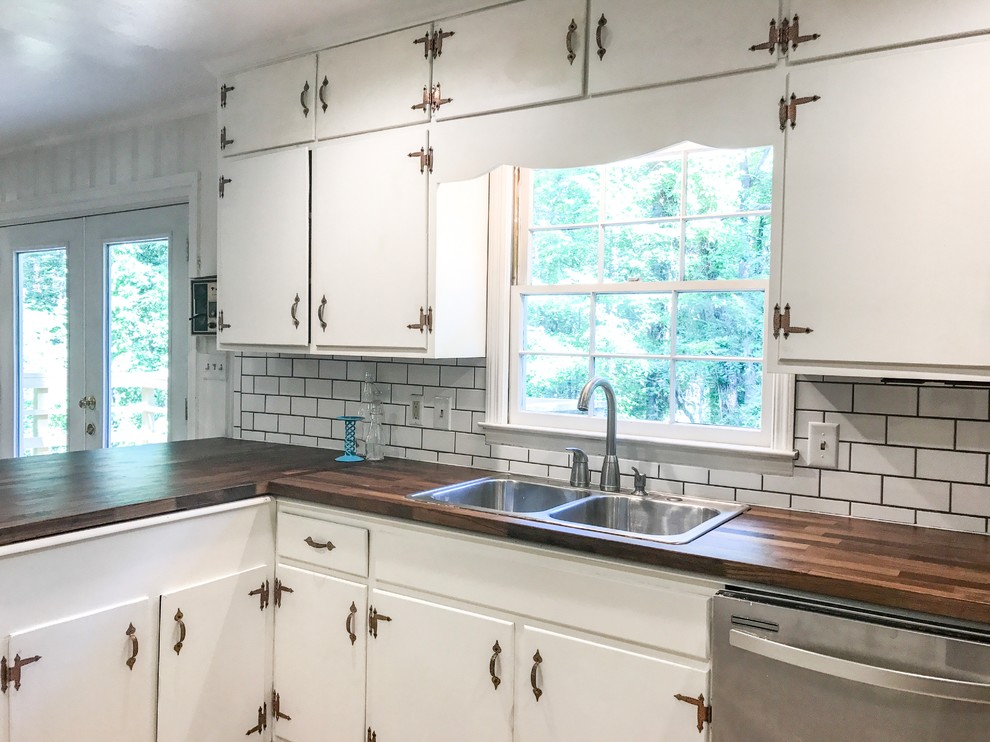 Mid-sized 1960s l-shaped ceramic tile and beige floor eat-in kitchen photo in Atlanta with a drop-in sink, flat-panel cabinets, white cabinets, wood countertops, white backsplash, porcelain backsplash, stainless steel appliances and a peninsula