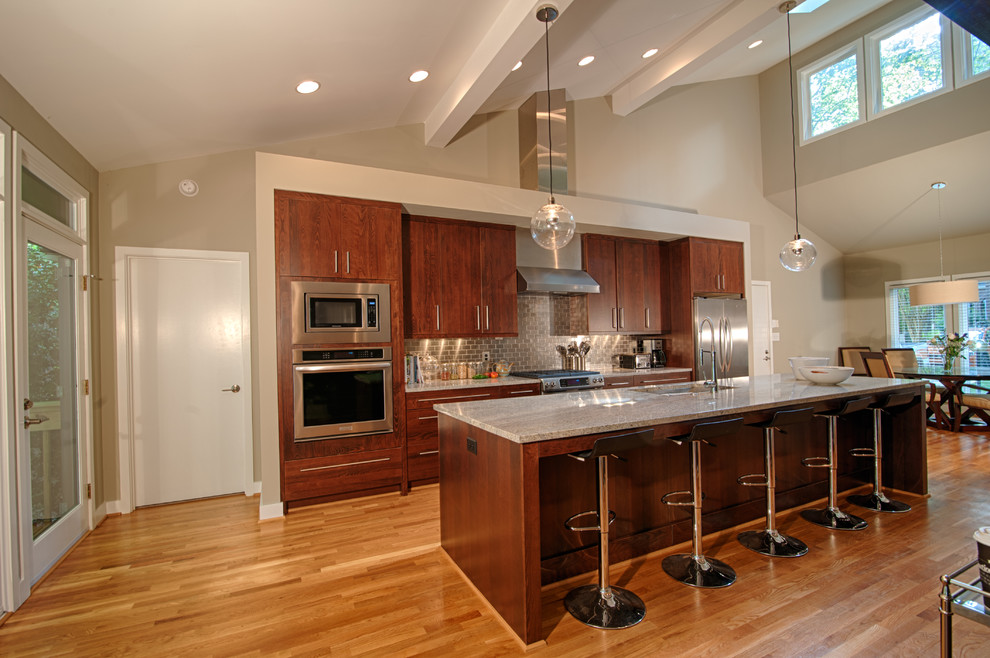 Inspiration for a contemporary galley light wood floor open concept kitchen remodel in San Francisco with a single-bowl sink, flat-panel cabinets, medium tone wood cabinets, granite countertops, metallic backsplash, metal backsplash, stainless steel appliances and an island