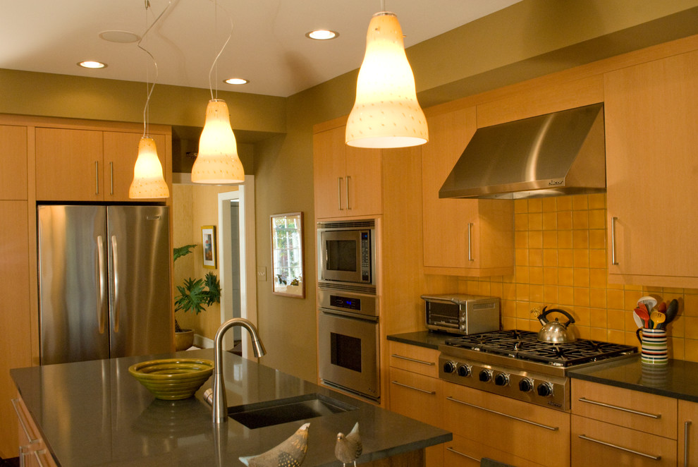 Exempel på ett avskilt modernt u-kök, med en undermonterad diskho, släta luckor, skåp i ljust trä, bänkskiva i kvarts, orange stänkskydd, stänkskydd i terrakottakakel, rostfria vitvaror, ljust trägolv och en köksö