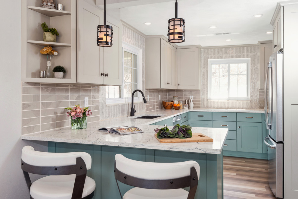 This is an example of a traditional u-shaped kitchen in Other with a submerged sink, shaker cabinets, grey splashback, stainless steel appliances, light hardwood flooring, a breakfast bar, beige floors, white worktops, turquoise cabinets and window splashback.