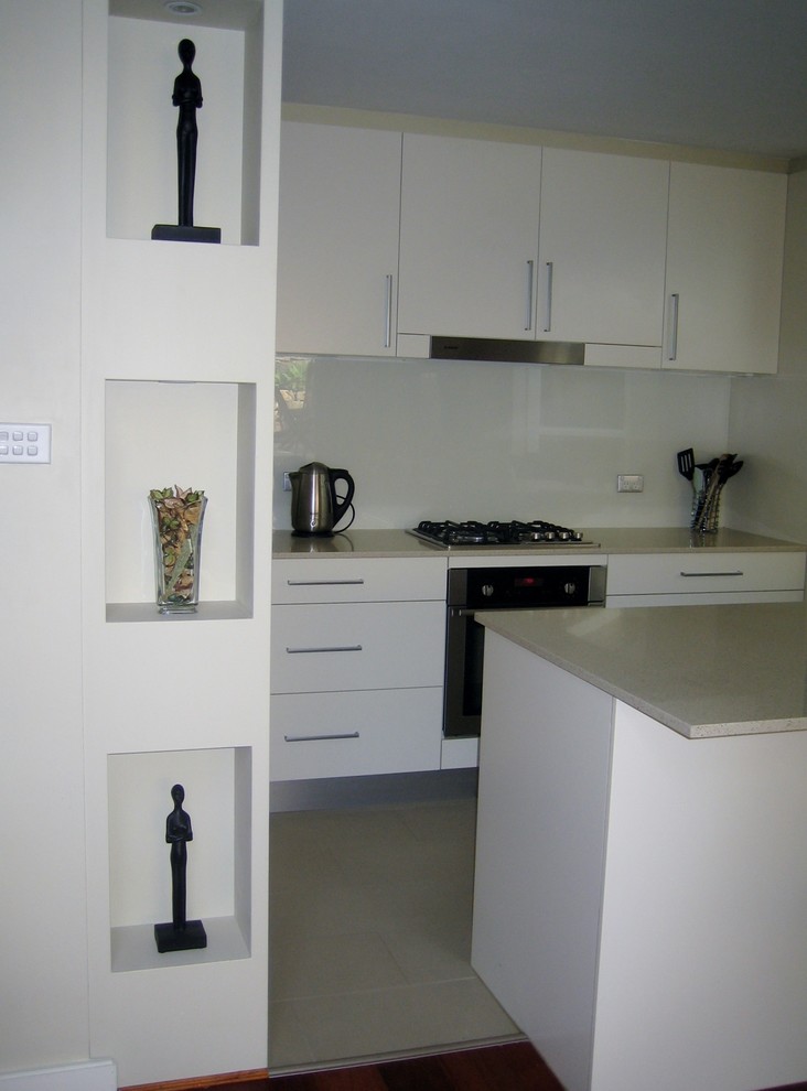 Bild på ett mellanstort funkis kök, med en undermonterad diskho, släta luckor, vita skåp, bänkskiva i kvarts, glaspanel som stänkskydd, rostfria vitvaror, klinkergolv i keramik och en köksö
