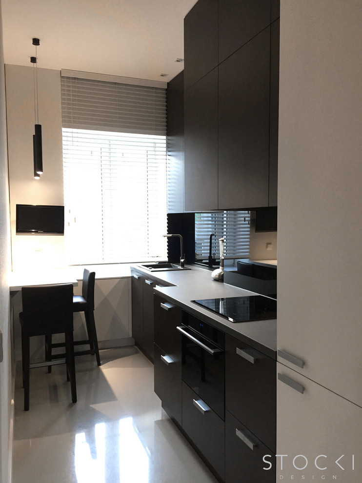 Inspiration for a small modern galley enclosed kitchen in New York with a submerged sink, flat-panel cabinets, dark wood cabinets, granite worktops, black splashback, glass sheet splashback, black appliances, no island and white floors.