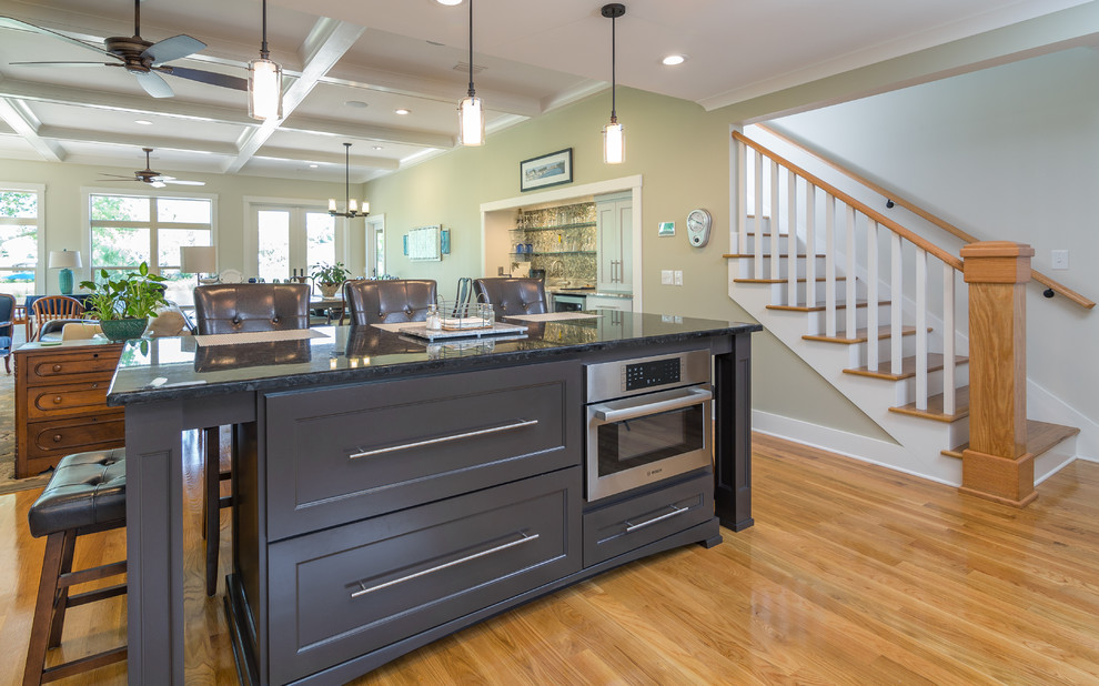 Inspiration for a mid-sized craftsman u-shaped light wood floor open concept kitchen remodel in Atlanta with an undermount sink, shaker cabinets, gray cabinets, solid surface countertops, black backsplash, porcelain backsplash, stainless steel appliances and an island