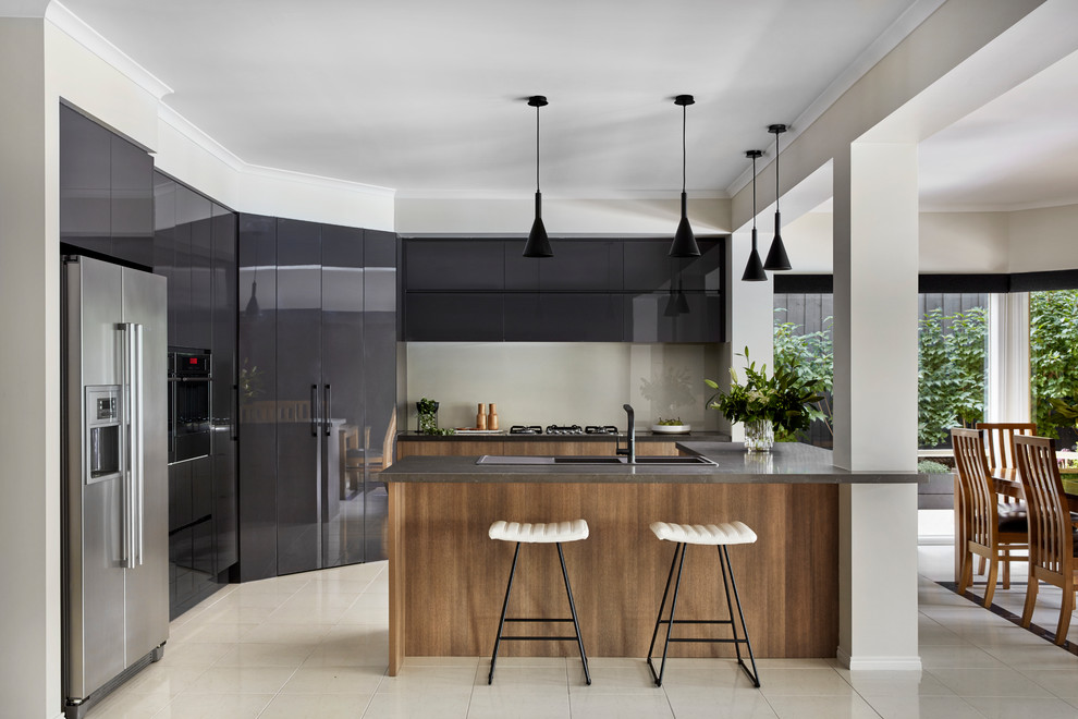 Moderne Wohnküche mit flächenbündigen Schrankfronten, grauen Schränken, Küchenrückwand in Beige, Glasrückwand, Küchengeräten aus Edelstahl, Kücheninsel, beigem Boden und grauer Arbeitsplatte in Melbourne