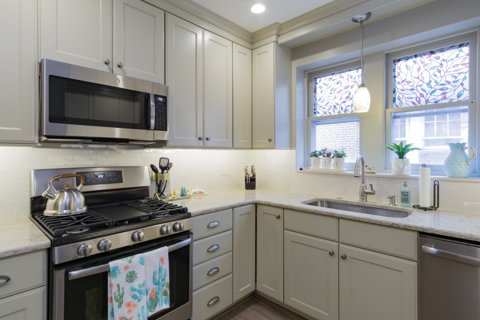 Exempel på ett mellanstort klassiskt beige beige kök, med en undermonterad diskho, luckor med infälld panel, gröna skåp, bänkskiva i kvarts, vitt stänkskydd, stänkskydd i keramik, rostfria vitvaror, laminatgolv och brunt golv