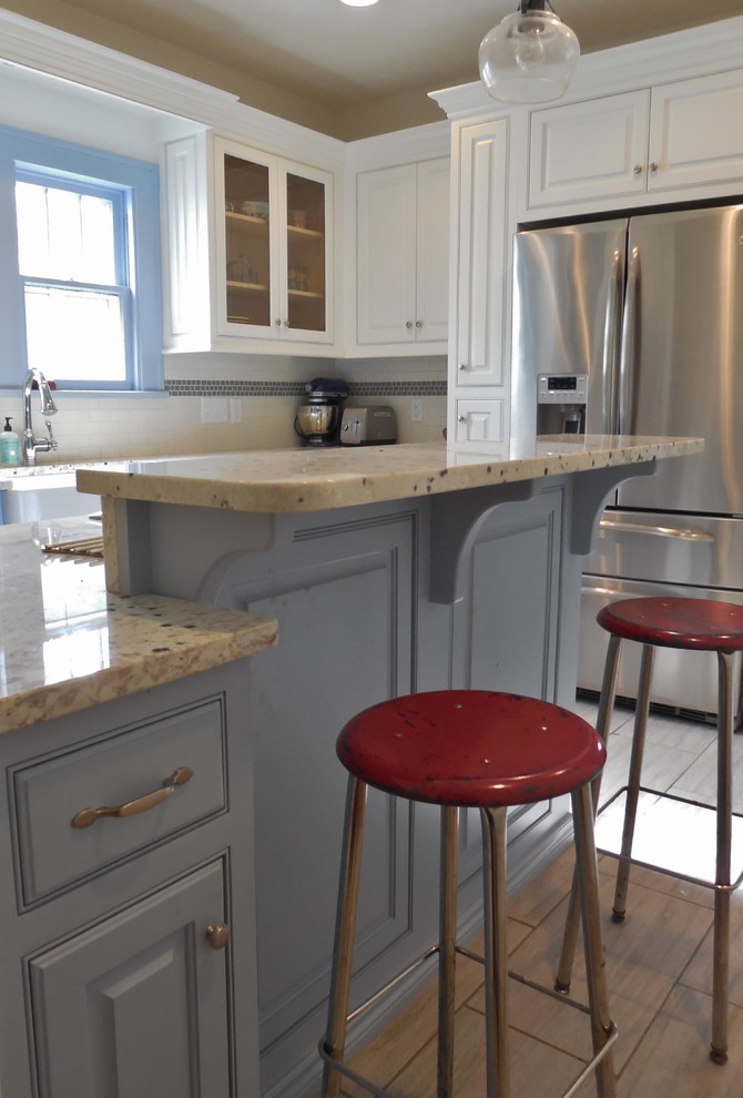 Bild på ett avskilt, litet lantligt u-kök, med en rustik diskho, luckor med upphöjd panel, blå skåp, granitbänkskiva, vitt stänkskydd, stänkskydd i tunnelbanekakel, rostfria vitvaror, klinkergolv i porslin och en halv köksö