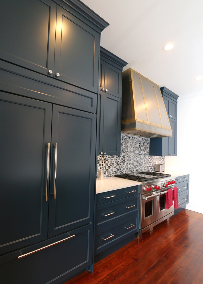 Mid-sized transitional medium tone wood floor and brown floor kitchen photo in New Orleans with recessed-panel cabinets, blue cabinets, multicolored backsplash, ceramic backsplash, an island and white countertops