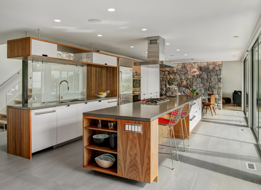 Inspiration for a contemporary gray floor open concept kitchen remodel in Boston with a double-bowl sink, flat-panel cabinets, white cabinets, white backsplash, glass sheet backsplash, stainless steel appliances, an island and gray countertops