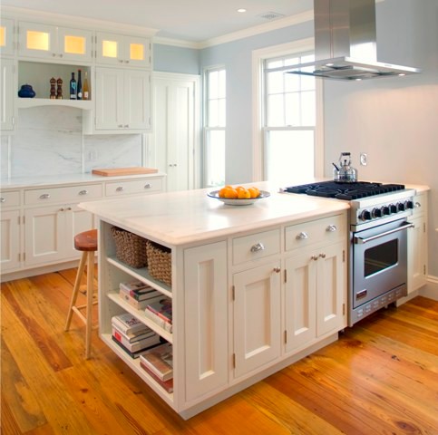 This is an example of a medium sized traditional galley kitchen pantry in Portland Maine with a belfast sink, white cabinets, onyx worktops, white splashback, stone slab splashback, stainless steel appliances, an island, shaker cabinets and light hardwood flooring.