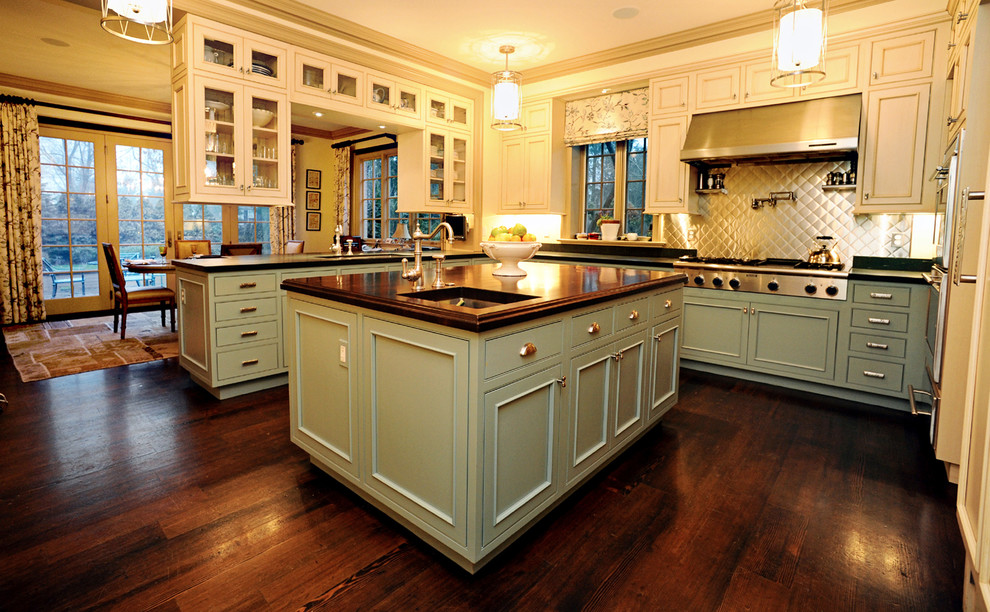 Exempel på ett stort klassiskt kök, med en nedsänkt diskho, luckor med infälld panel, beige skåp, träbänkskiva, stänkskydd med metallisk yta, stänkskydd i metallkakel, rostfria vitvaror, mörkt trägolv, en köksö och brunt golv