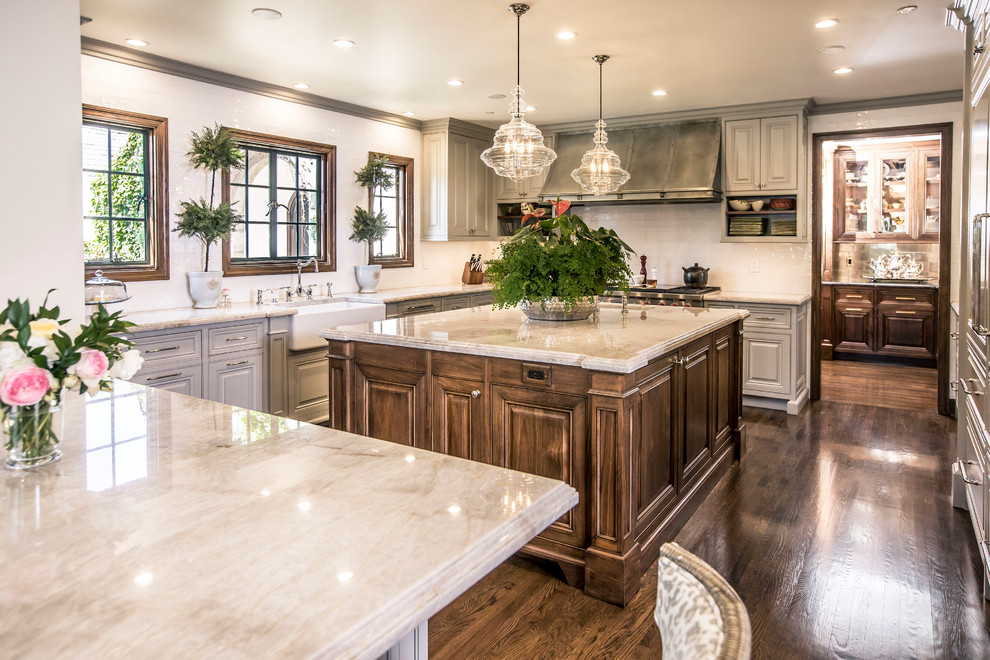 Inspiration for a timeless u-shaped dark wood floor and brown floor kitchen remodel in Los Angeles with a farmhouse sink, raised-panel cabinets, gray cabinets, white backsplash, paneled appliances, an island and beige countertops