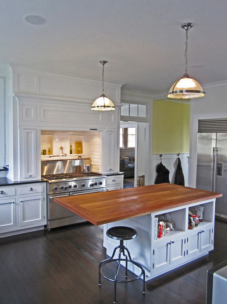 Example of a classic kitchen design in New York with stainless steel appliances and wood countertops