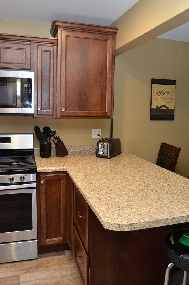 Exempel på ett stort klassiskt beige beige kök, med luckor med infälld panel, skåp i mörkt trä, laminatbänkskiva, en halv köksö, en undermonterad diskho, rostfria vitvaror, ljust trägolv och brunt golv