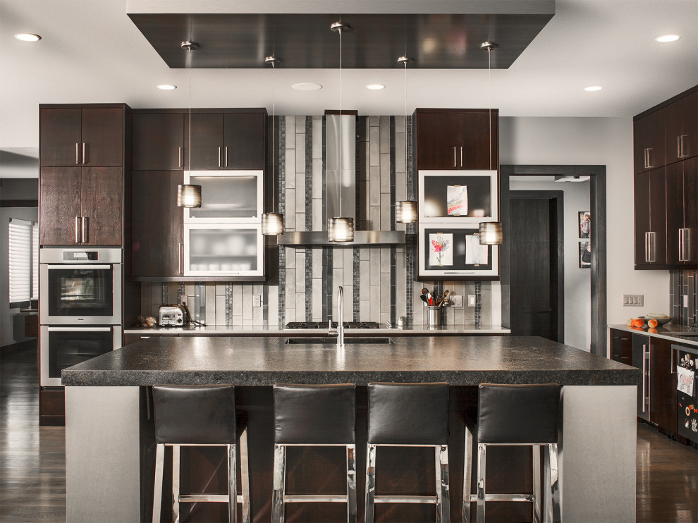 Example of a trendy dark wood floor kitchen design in Denver with flat-panel cabinets, dark wood cabinets, multicolored backsplash, stainless steel appliances and an island