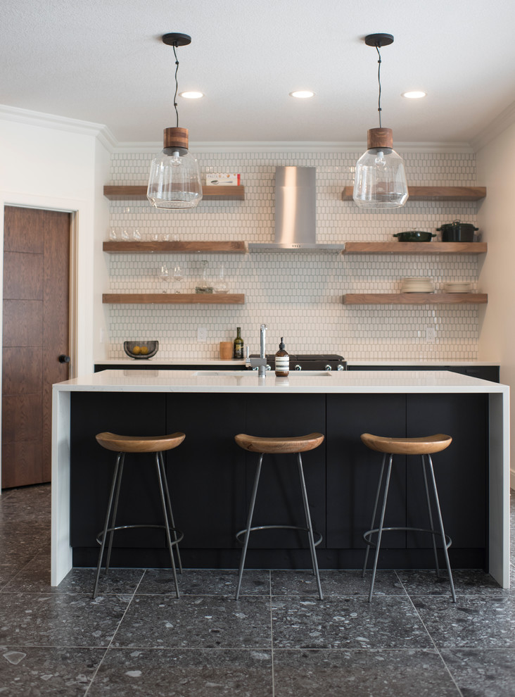Trendy galley black floor kitchen photo in Edmonton with an integrated sink, flat-panel cabinets, black cabinets, white backsplash, an island and white countertops