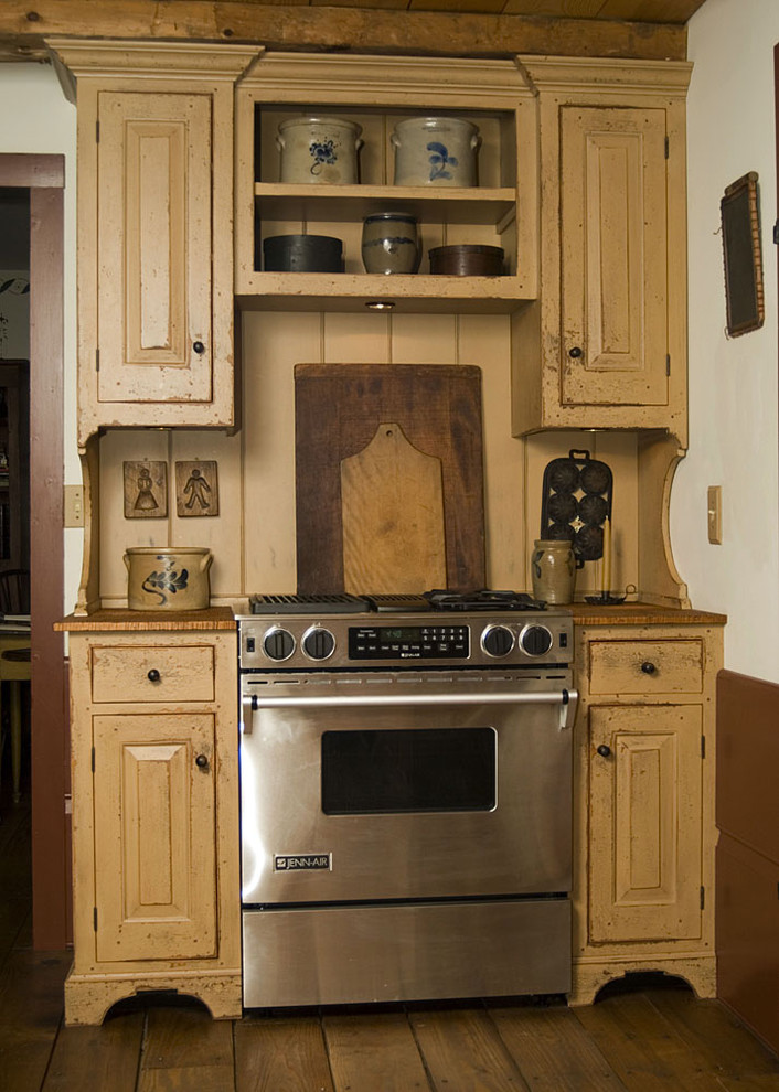 Ejemplo de cocina tradicional con encimera de madera y puertas de armario con efecto envejecido