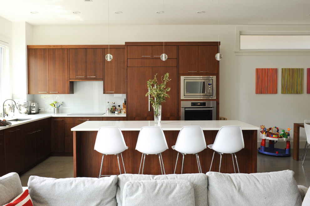 Immagine di una cucina contemporanea con lavello sottopiano, ante lisce, ante in legno bruno, paraspruzzi bianco, paraspruzzi con lastra di vetro e elettrodomestici da incasso