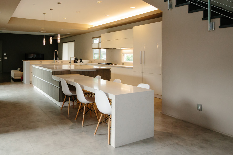 Bild på ett stort funkis kök, med en undermonterad diskho, släta luckor, vita skåp, bänkskiva i kvarts, integrerade vitvaror, cementgolv, en köksö och grått golv