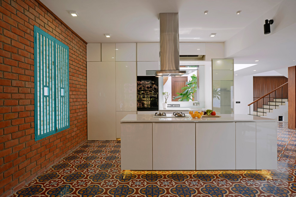 Источник вдохновения для домашнего уюта: параллельная, глянцевая кухня-гостиная в морском стиле с плоскими фасадами, белыми фасадами, техникой из нержавеющей стали, полом из керамической плитки, островом и разноцветным полом