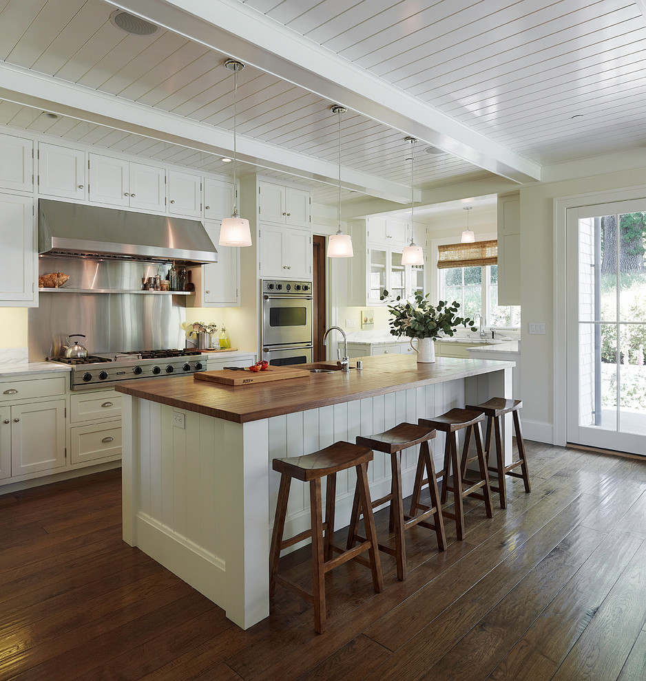 Elegant u-shaped dark wood floor open concept kitchen photo in San Francisco with stainless steel appliances, wood countertops, white cabinets, shaker cabinets, metallic backsplash, metal backsplash, an undermount sink and an island