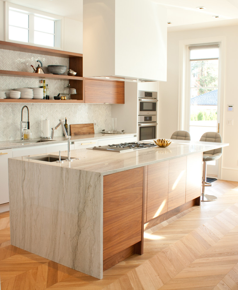 Cette image montre une cuisine design en bois brun avec un évier encastré, un placard sans porte, un électroménager en acier inoxydable, parquet clair et îlot.