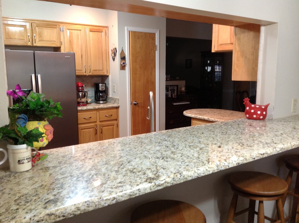 Example of a country u-shaped eat-in kitchen design in Miami with an undermount sink, raised-panel cabinets, yellow cabinets, granite countertops, beige backsplash, stone tile backsplash and black appliances