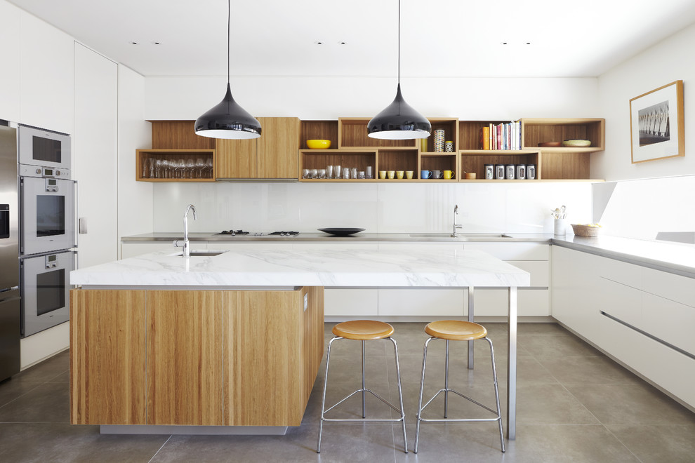 Design ideas for a medium sized midcentury u-shaped kitchen/diner in Melbourne with a double-bowl sink, flat-panel cabinets, white cabinets, marble worktops, white splashback, concrete flooring, an island, glass sheet splashback and stainless steel appliances.