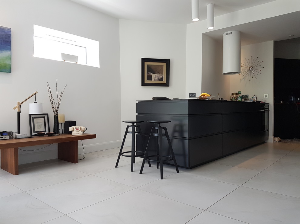 This is an example of a large contemporary single-wall enclosed kitchen in Dublin with black cabinets, wood worktops, grey splashback and a breakfast bar.