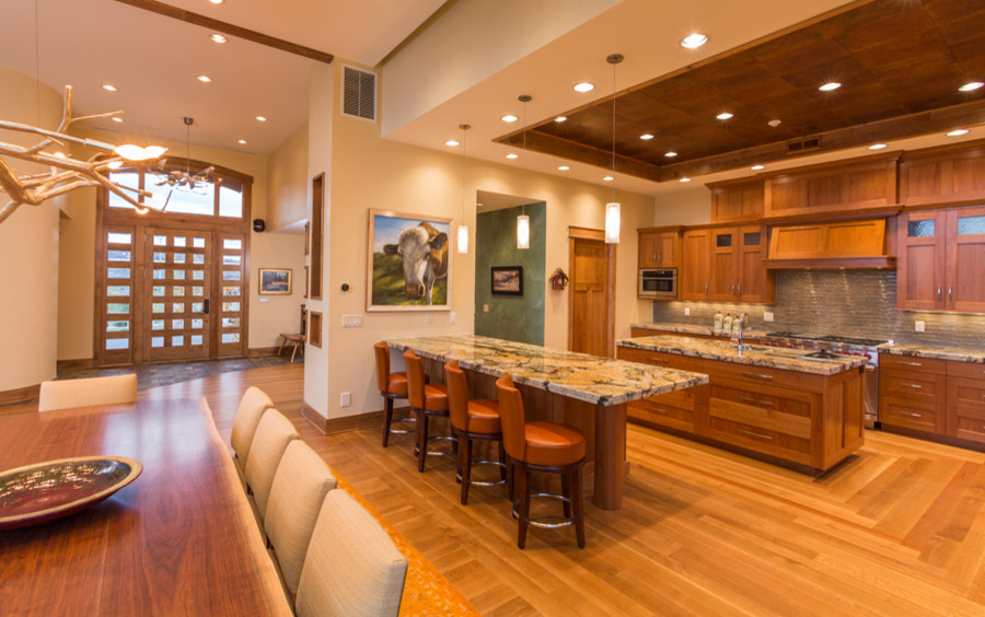 This is an example of a large rustic u-shaped kitchen/diner in Denver with a single-bowl sink, recessed-panel cabinets, medium wood cabinets, granite worktops, grey splashback, ceramic splashback, stainless steel appliances, medium hardwood flooring, multiple islands and brown floors.