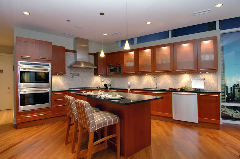 Idée de décoration pour une cuisine américaine design en L et bois brun de taille moyenne avec un placard à porte vitrée, un plan de travail en onyx et un sol en bois brun.