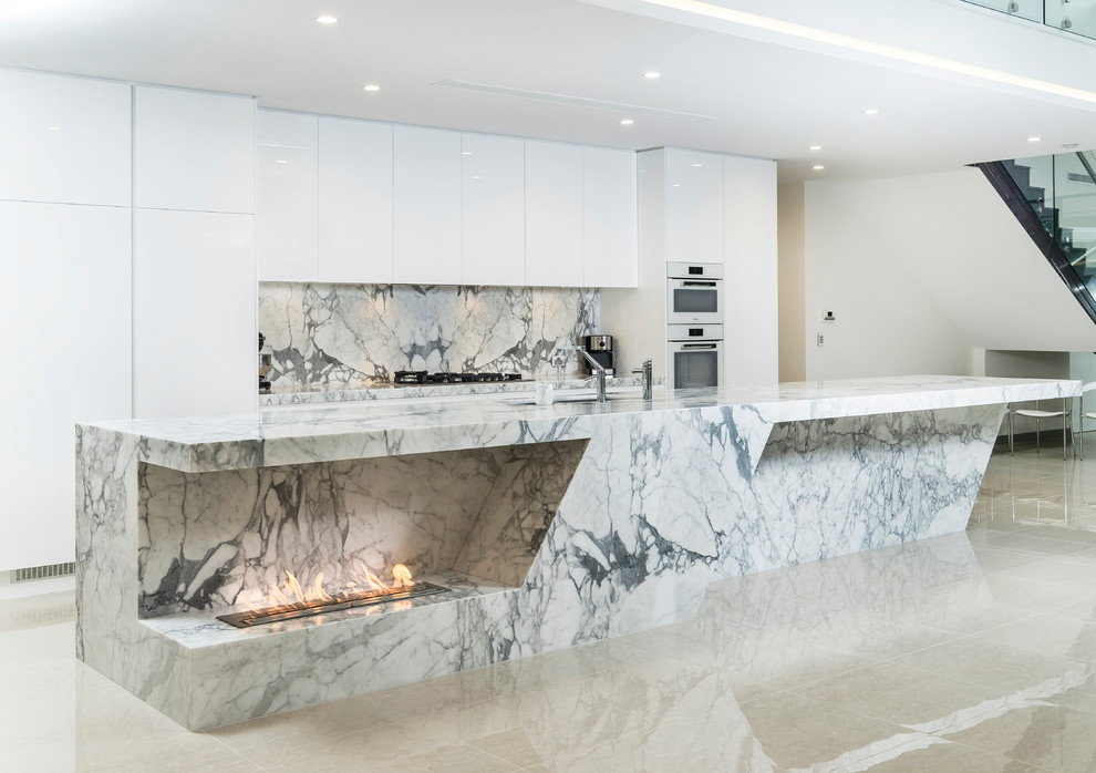 This is an example of a large contemporary galley open plan kitchen in Sydney with an island, a submerged sink, white cabinets, marble worktops, stone slab splashback, stainless steel appliances and grey splashback.