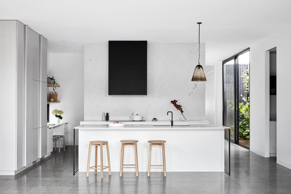 Imagen de cocinas en L moderna con fregadero bajoencimera, armarios con paneles lisos, suelo de cemento, una isla, suelo gris, encimeras blancas y con blanco y negro