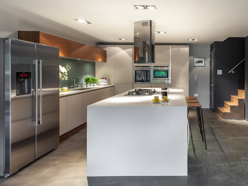 Photo of a contemporary galley kitchen in London with a submerged sink, flat-panel cabinets, grey cabinets, concrete worktops, stainless steel appliances, concrete flooring and an island.