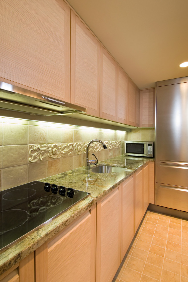 Example of a small eclectic u-shaped terra-cotta tile enclosed kitchen design in New York with an undermount sink, flat-panel cabinets, light wood cabinets, granite countertops, green backsplash, ceramic backsplash and stainless steel appliances