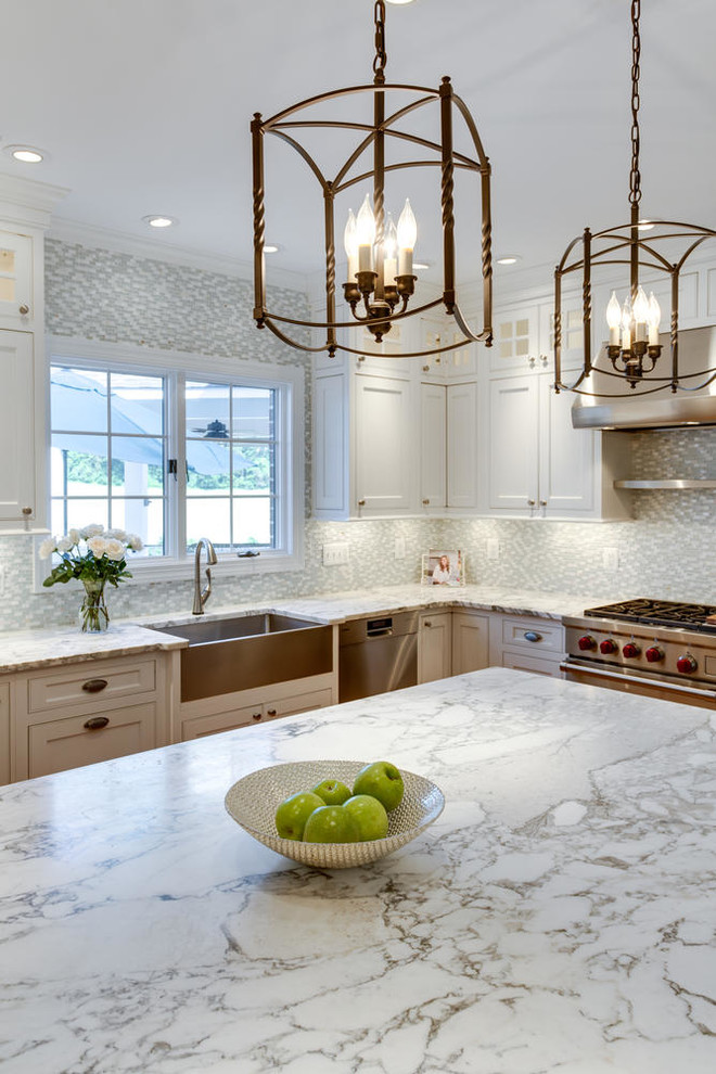 Klassisk inredning av ett kök, med en rustik diskho, skåp i shakerstil, vita skåp, marmorbänkskiva, flerfärgad stänkskydd, rostfria vitvaror, mellanmörkt trägolv, en köksö och stänkskydd i glaskakel