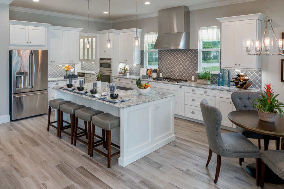 Inspiration for a mid-sized transitional porcelain tile and gray floor kitchen remodel in Orlando with a single-bowl sink, shaker cabinets, white cabinets, quartz countertops, gray backsplash, glass tile backsplash, stainless steel appliances, an island and beige countertops