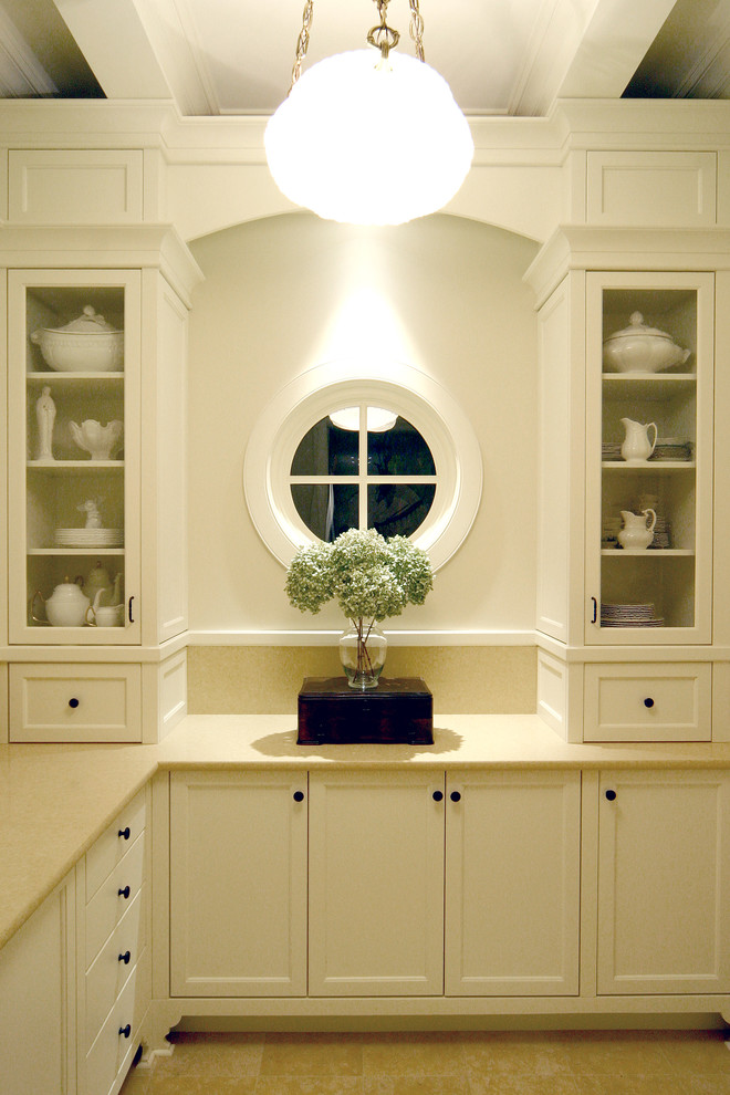 Cette image montre une grande arrière-cuisine traditionnelle en U avec un placard à porte vitrée et des portes de placard blanches.