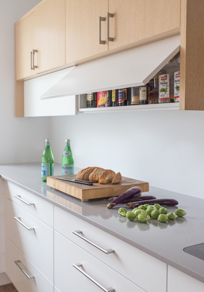 Immagine di una cucina moderna con ante lisce, ante bianche e top in quarzo composito