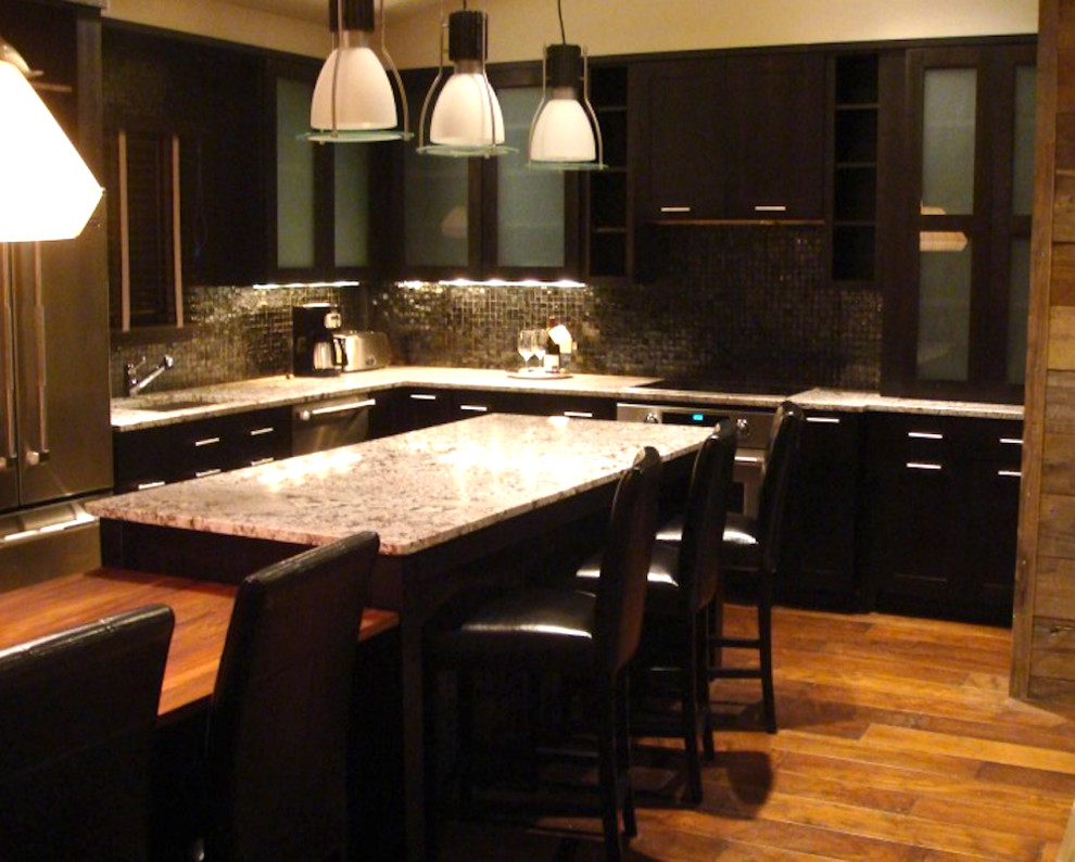 Design ideas for a large classic l-shaped kitchen/diner in Tampa with a submerged sink, flat-panel cabinets, dark wood cabinets, granite worktops, metallic splashback, mosaic tiled splashback, stainless steel appliances, dark hardwood flooring, an island and brown floors.