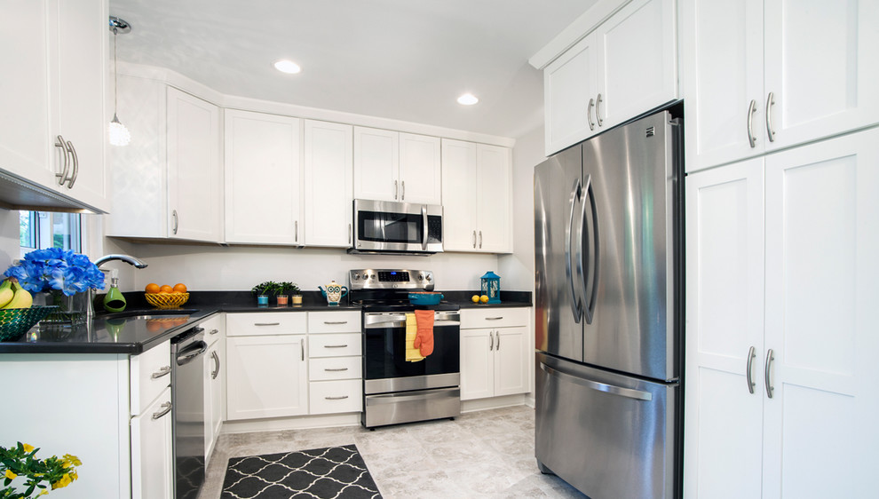Photo of a large contemporary l-shaped enclosed kitchen in Chicago with white cabinets, stainless steel appliances, a submerged sink, recessed-panel cabinets, engineered stone countertops, white splashback, ceramic flooring, no island and grey floors.