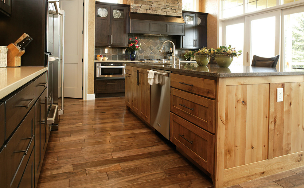 Inspiration för avskilda, mellanstora rustika l-kök, med en undermonterad diskho, luckor med infälld panel, skåp i mörkt trä, bänkskiva i kvarts, grått stänkskydd, stänkskydd i stenkakel, rostfria vitvaror, mellanmörkt trägolv, en köksö och brunt golv