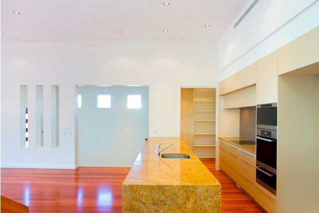 Foto di una cucina design con lavello sottopiano, ante lisce, ante beige, top in granito, paraspruzzi grigio, paraspruzzi con lastra di vetro e elettrodomestici in acciaio inossidabile