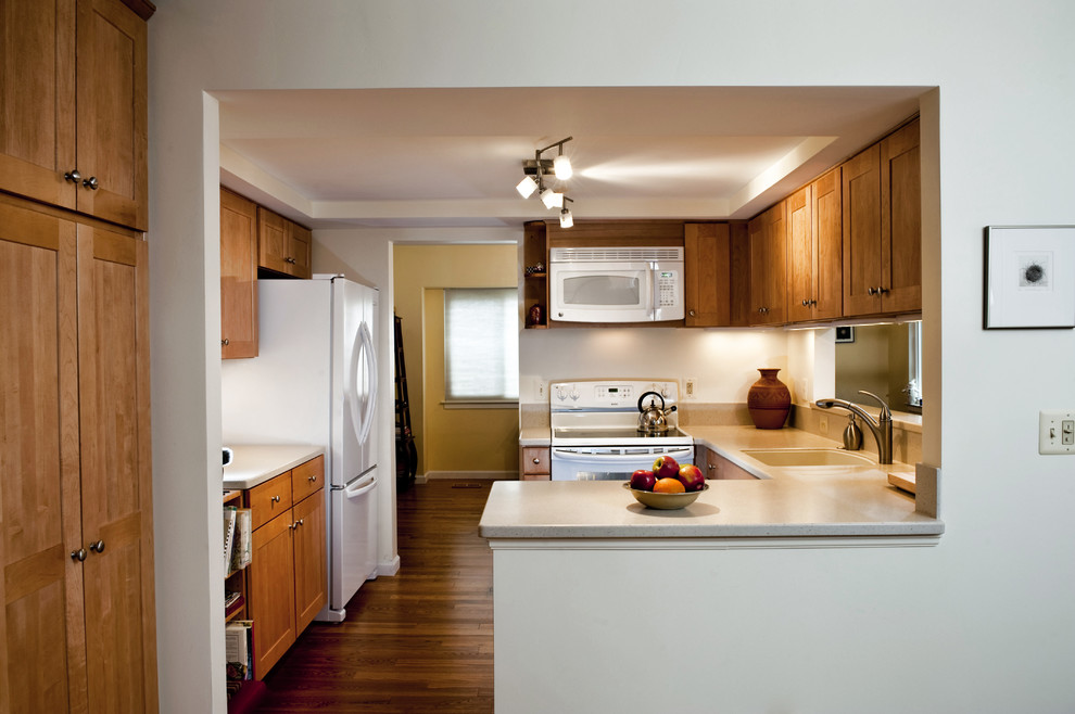 Inspiration for a mid-sized contemporary u-shaped medium tone wood floor enclosed kitchen remodel in DC Metro with white appliances, an undermount sink, shaker cabinets, medium tone wood cabinets, solid surface countertops and a peninsula