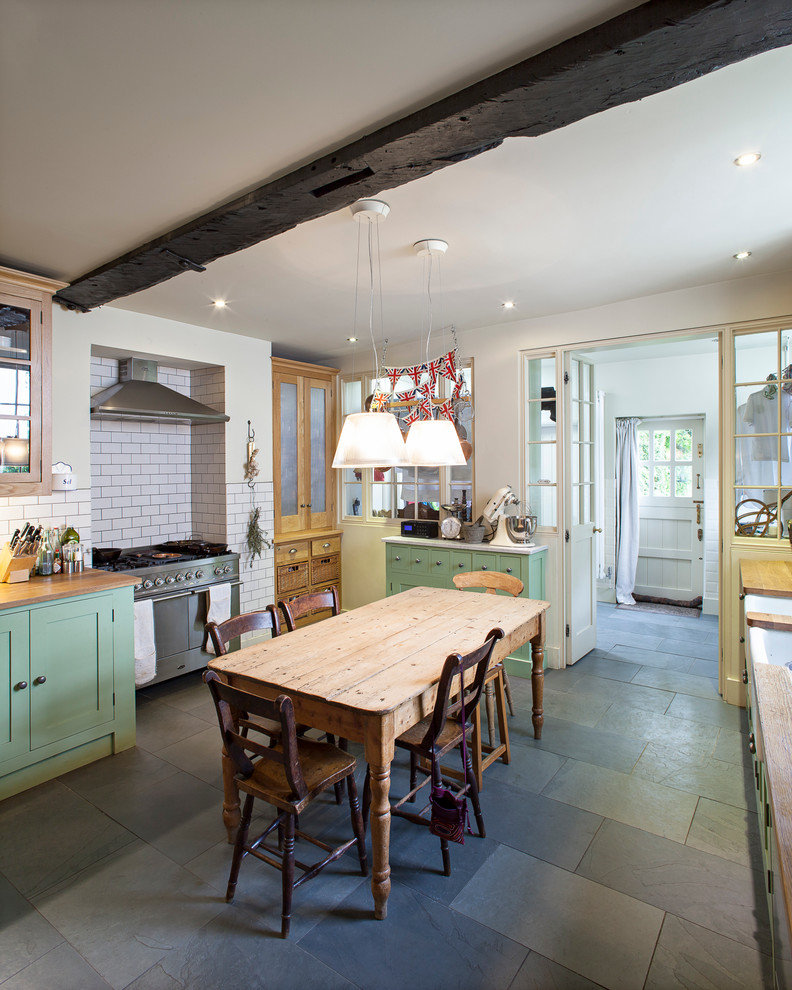 ロンドンにあるシャビーシック調のおしゃれなキッチン (エプロンフロントシンク、シェーカースタイル扉のキャビネット、緑のキャビネット、白いキッチンパネル、サブウェイタイルのキッチンパネル、シルバーの調理設備) の写真