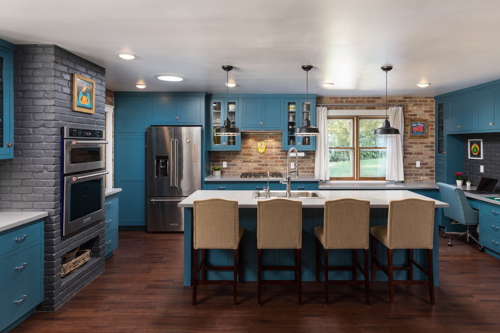 Foto på ett vintage vit u-kök, med en nedsänkt diskho, skåp i shakerstil, blå skåp, rött stänkskydd, stänkskydd i tegel, rostfria vitvaror, mörkt trägolv, en köksö och brunt golv
