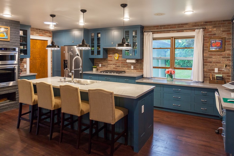 Klassisk inredning av ett kök och matrum, med en nedsänkt diskho, skåp i shakerstil, blå skåp, bänkskiva i koppar, rött stänkskydd, stänkskydd i tegel, rostfria vitvaror, mörkt trägolv, en köksö och brunt golv
