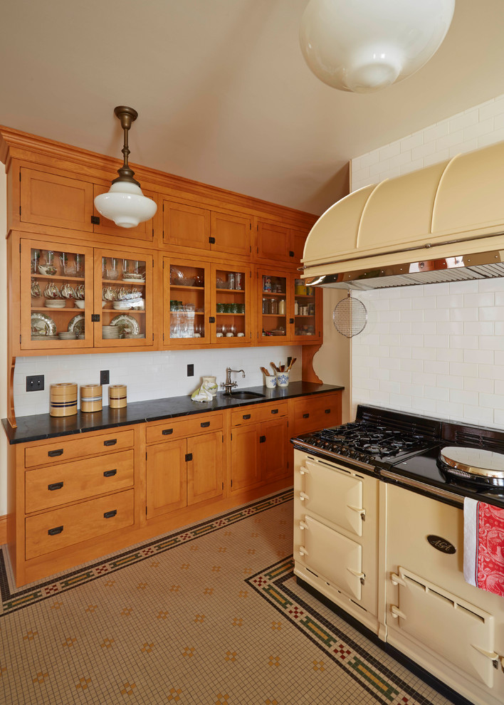 Huge 1950s ceramic tile and multicolored floor kitchen photo in Other with a farmhouse sink, beaded inset cabinets, medium tone wood cabinets, granite countertops, black backsplash and black countertops