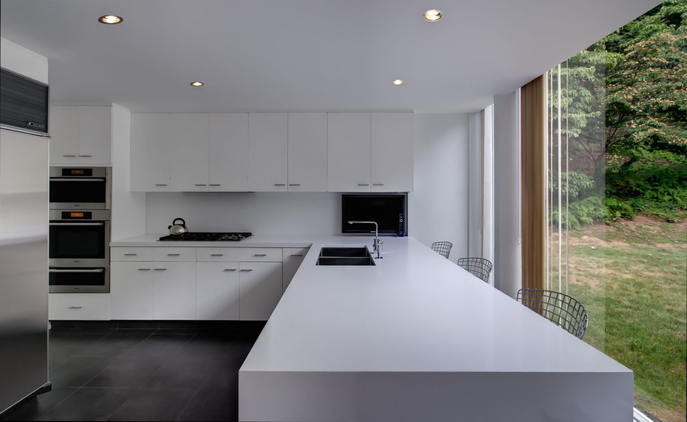 Exempel på ett modernt kök, med rostfria vitvaror, en dubbel diskho, bänkskiva i kvarts och svart golv