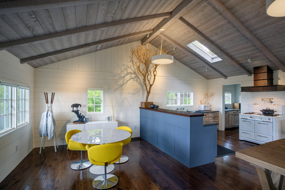 Rustik inredning av ett litet kök, med skåp i shakerstil, blå skåp, vita vitvaror, mellanmörkt trägolv, en halv köksö, brunt golv, en undermonterad diskho, vitt stänkskydd och bänkskiva i kvartsit
